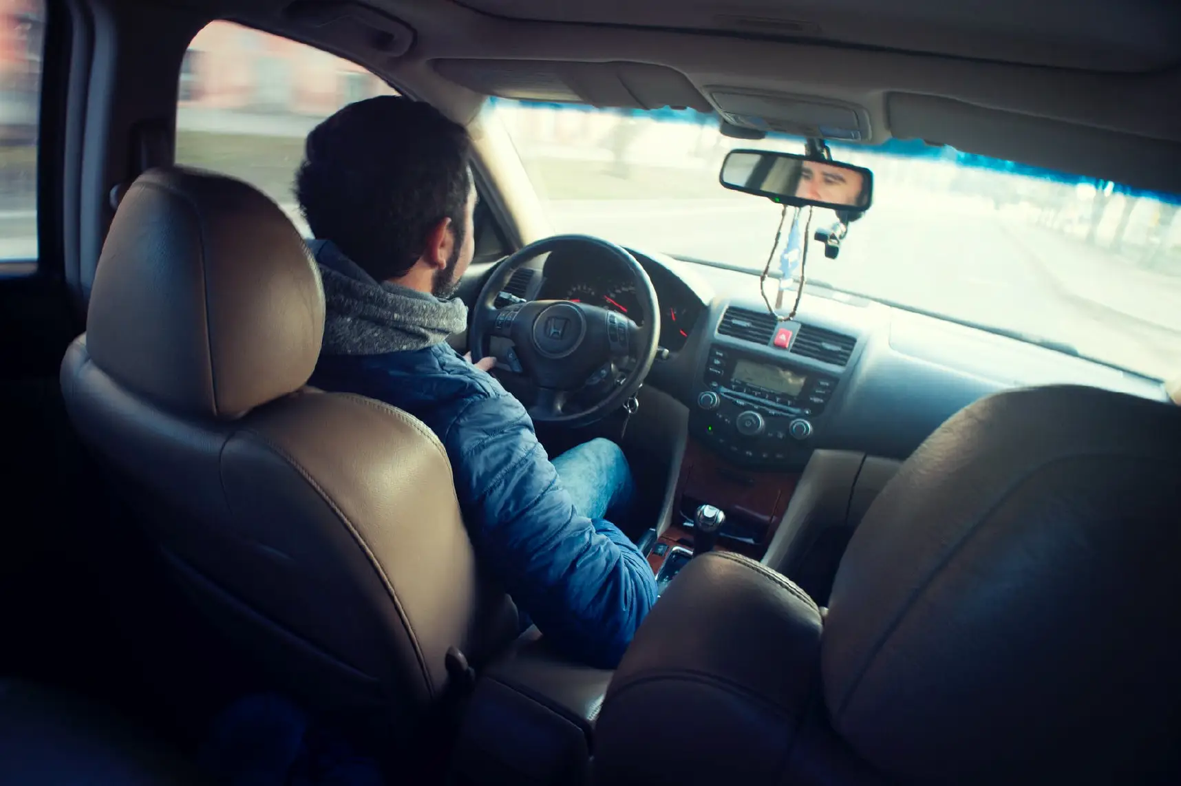 view from the backseat inside a car, with a man driving