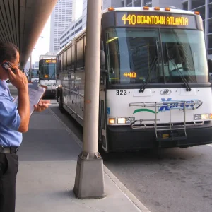 xpress GRTA bus operator outside bus, standing on sidewalk, talking on a cell phone