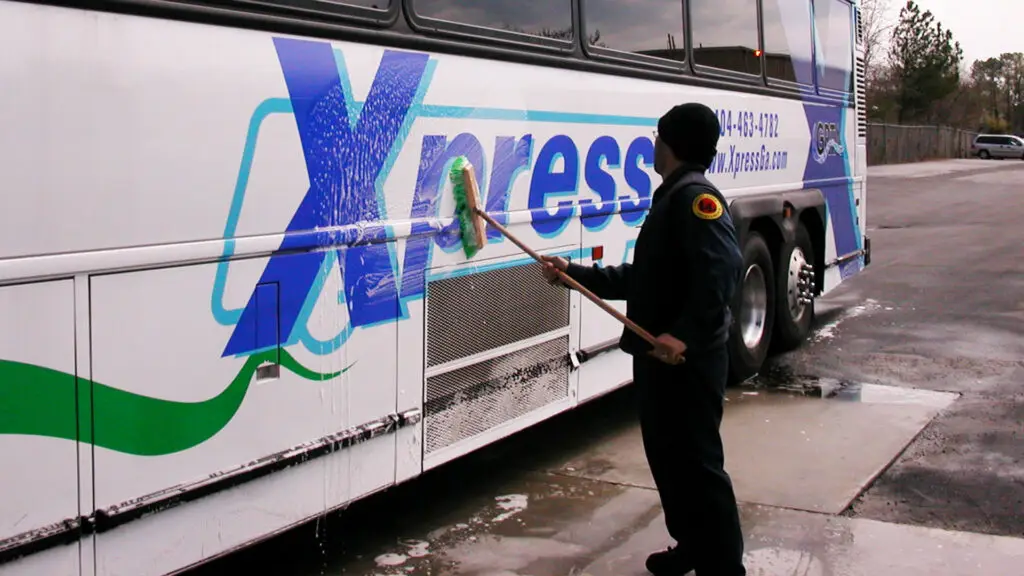 Xpress staff worker washing side of Xpress bus